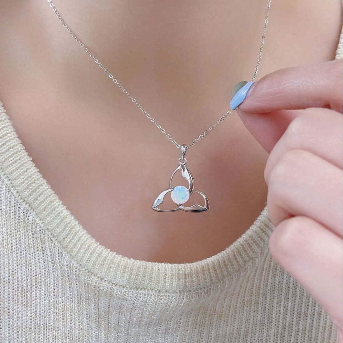 Silver Trinity necklace with opal pendant, worn by a person looking elegant.